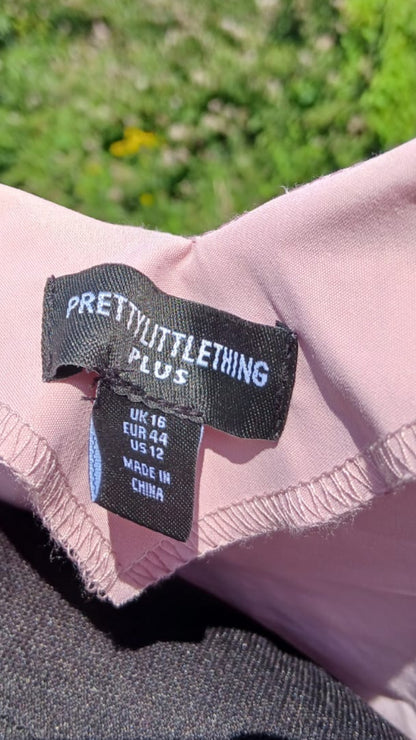Close-up of a pink puff sleeve top tag reading PRETTY LITTLE THING PLUS.