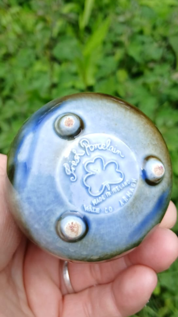 The bottom of a miniature handmade ceramic cauldron with a handle with the stamp of  Wade Irish Porcelain.