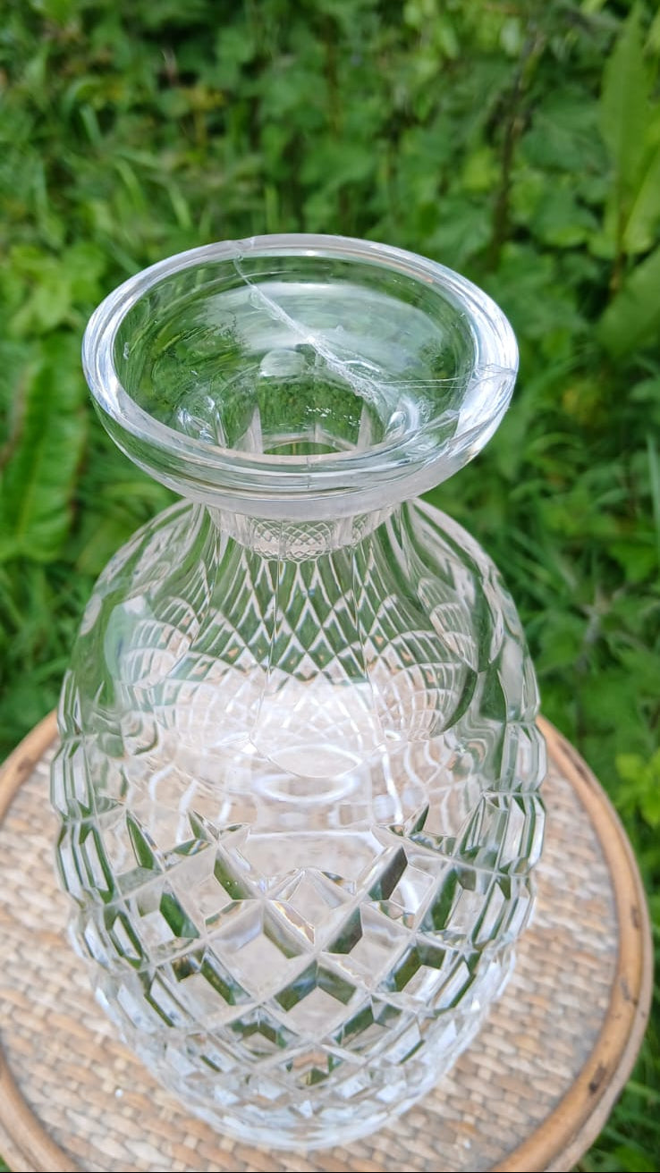 A clear cut-glass decanter with a diamond-patterned body and a flared rim