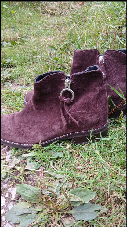 A pair of brown suede ankle boots with silver-tone hardware.