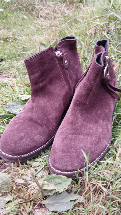 A pair of dark plum purple suede ankle boots with side zippers.