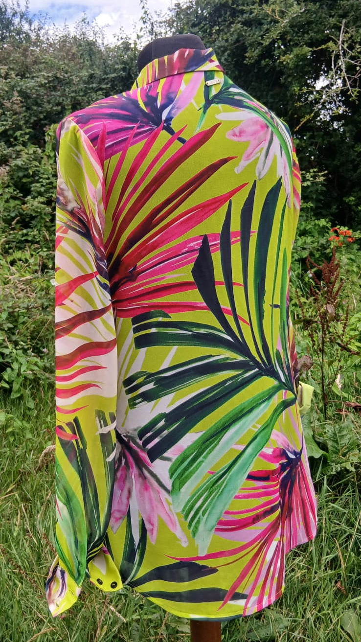 A long-sleeve button-up shirt with a bold tropical leaf print in neon yellow, pink, green, and black.