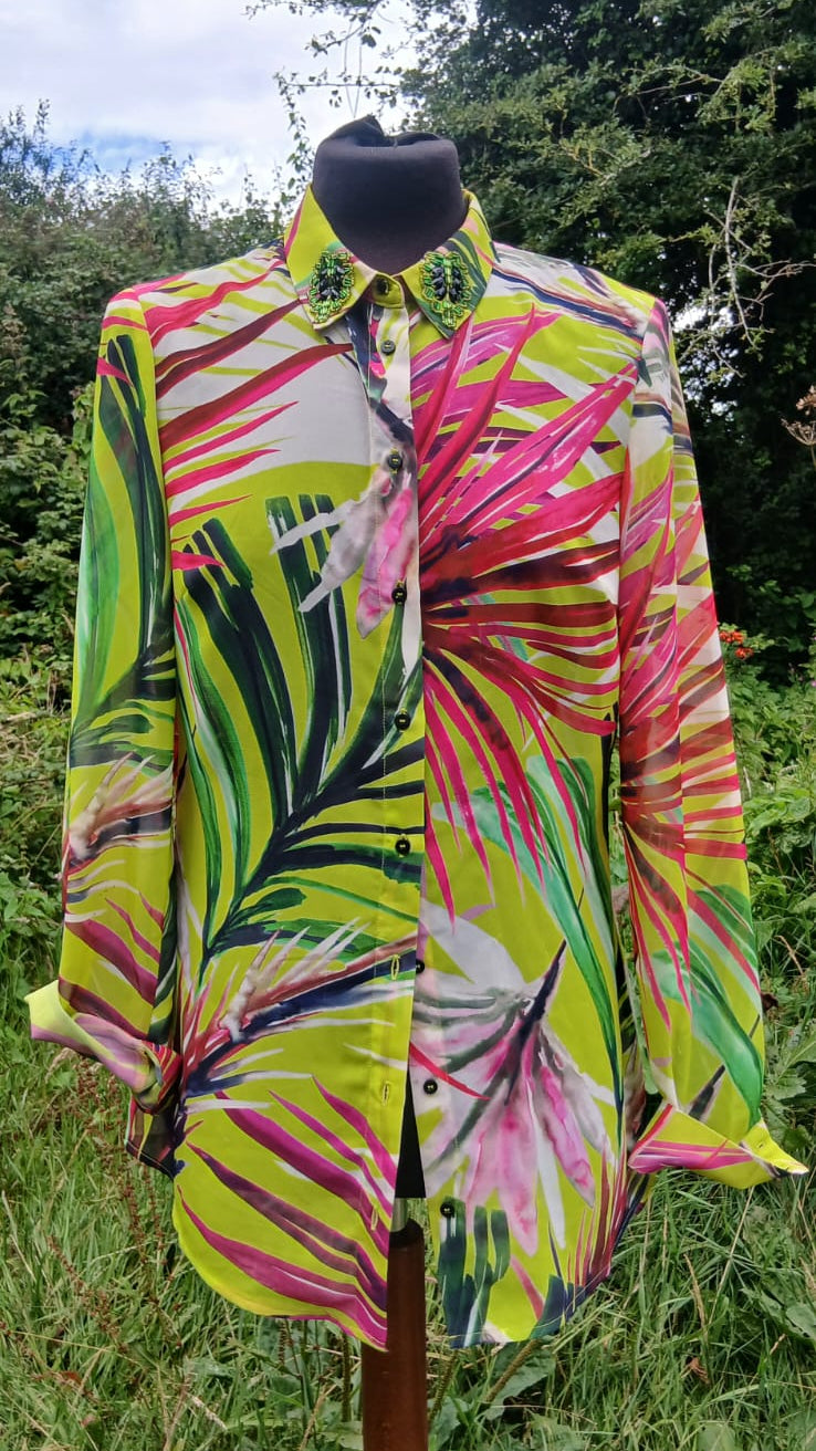 A long-sleeve button-up shirt with a bold tropical leaf print in neon yellow-green, pink, and black, .