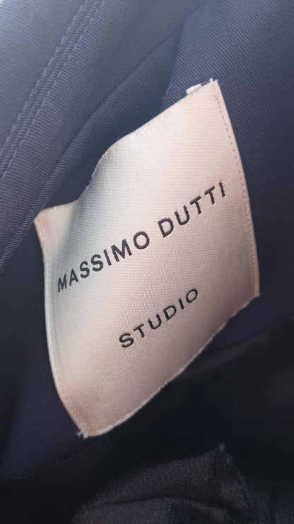 Close-up of a fabric label reading 'MASSIMO DUTTI STUDIO' sewn onto dark navy blue clothing.