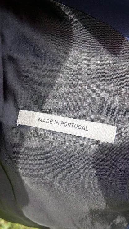 Close-up of a dark fabric garment with a white label reading 'MADE IN PORTUGAL' sewn onto the inside.