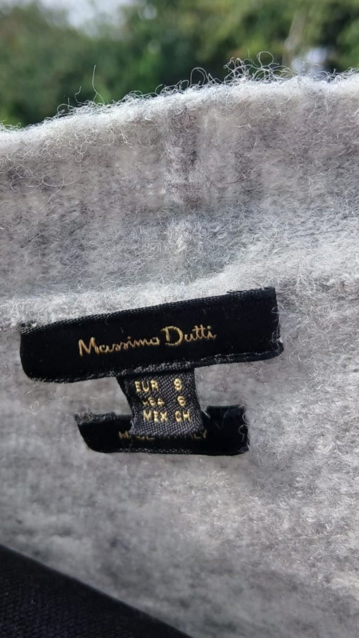 Close-up of a light gray fuzzy fabric item with a black sewn-in label reading Massimo Dutti.