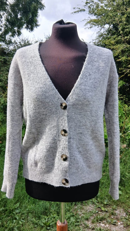 A light gray knit cardigan sweater with a V-neck, long sleeves, and four dark brown buttons.