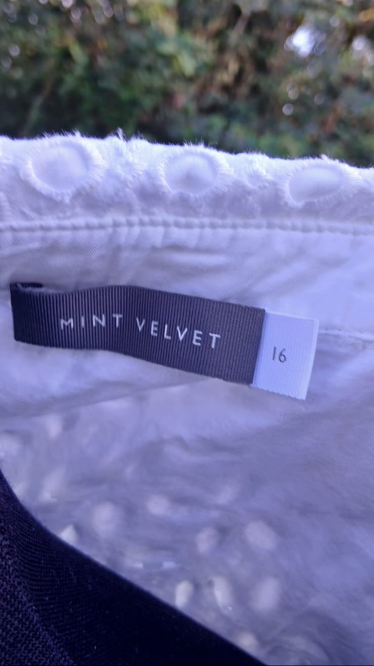 Close-up of a white textured garment with a dark gray brand tag reading 'MINT VELVET' and size '16'.