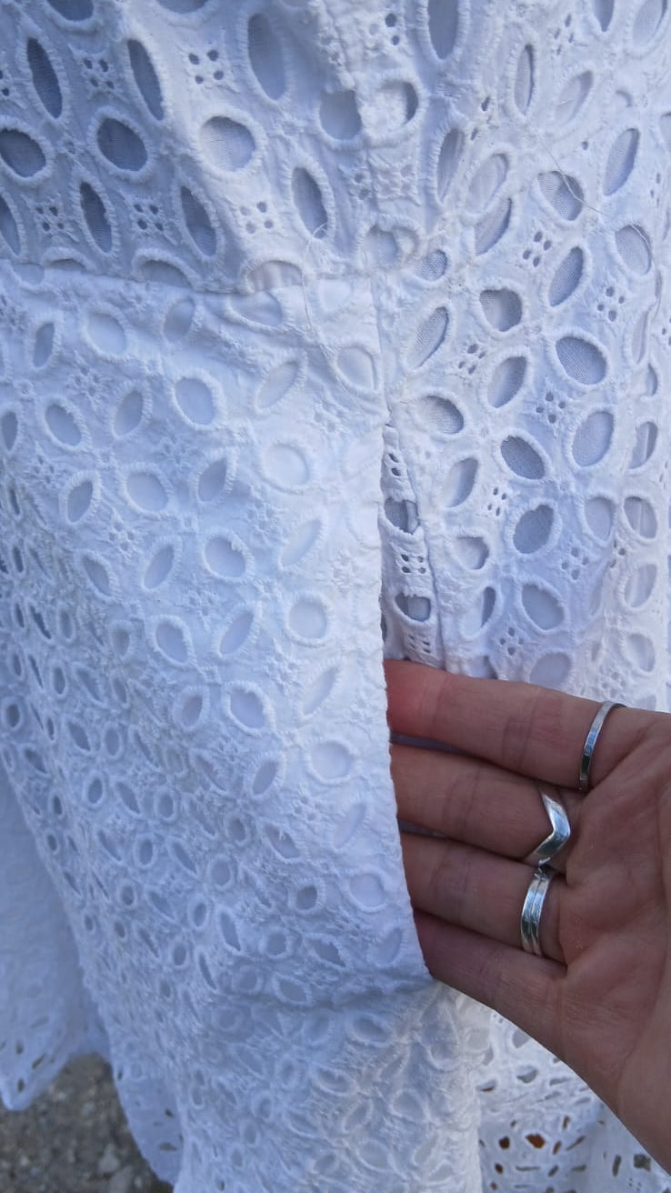 Close-up of a white eyelet lace garment showing a side pocket.