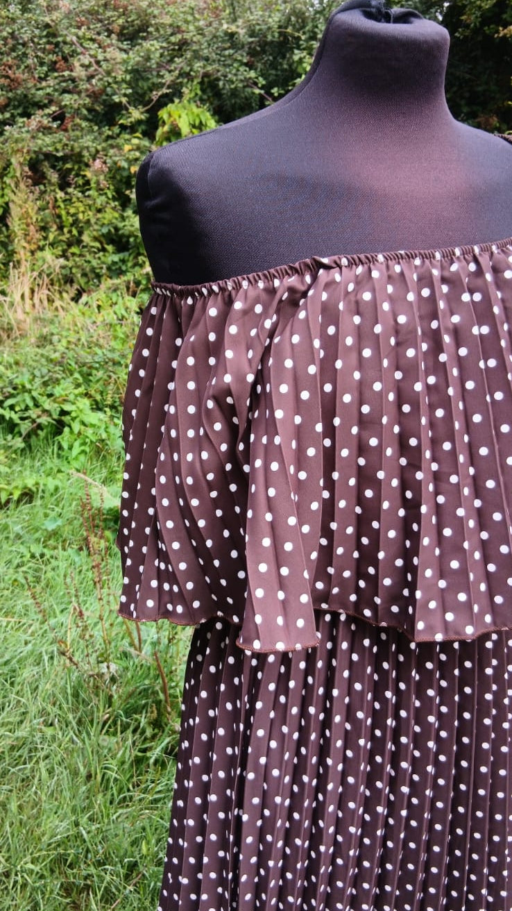 An off-the-shoulder midi dress with white polka dots on a brown background