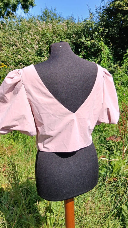 A back view of light pink short-sleeve blouse with puff sleeves and a deep V back.