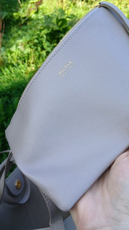 A close-up of a  light gray pebbled leather pouch with gold-tone 'POLENE' branding.