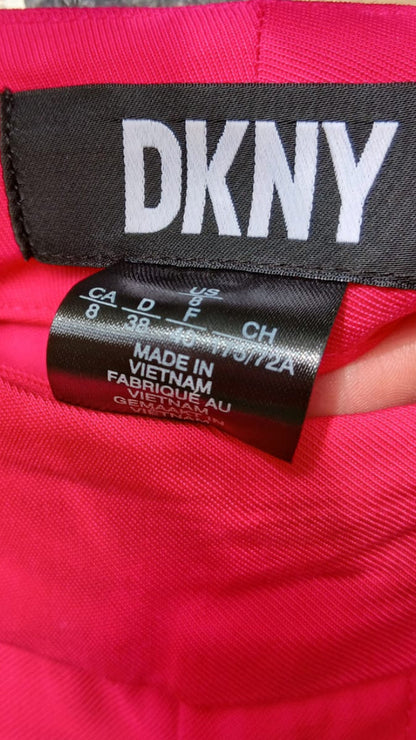 Close-up of a bright pink DKNY trousers showing the black brand label and size tag.