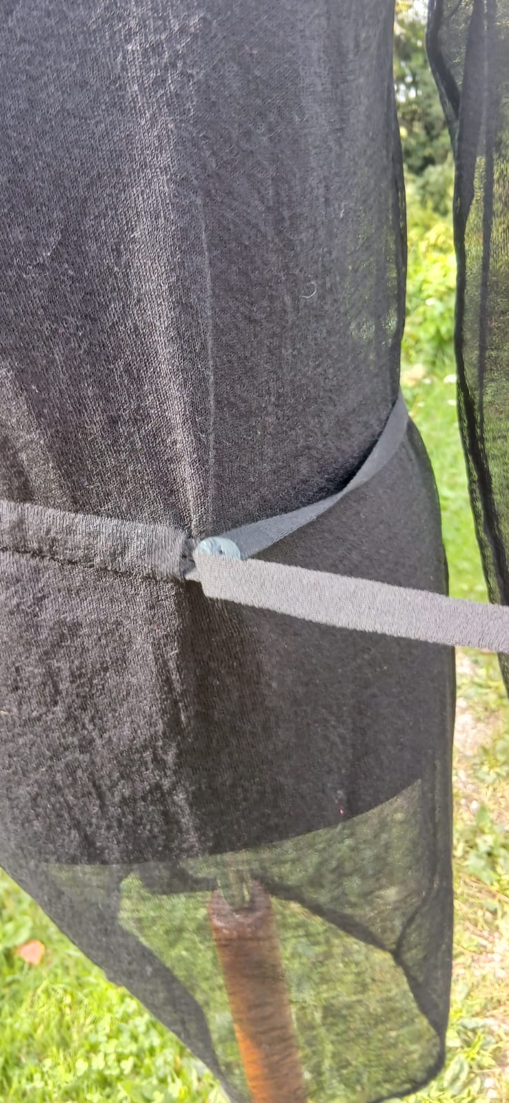 Close-up of a black mesh Sarah Pacini dress tied with a belt.