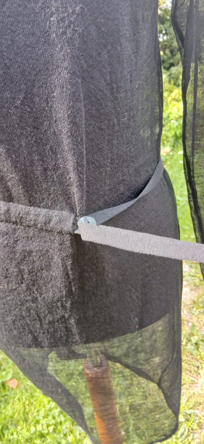 Close-up of a black mesh Sarah Pacini dress tied with a belt.