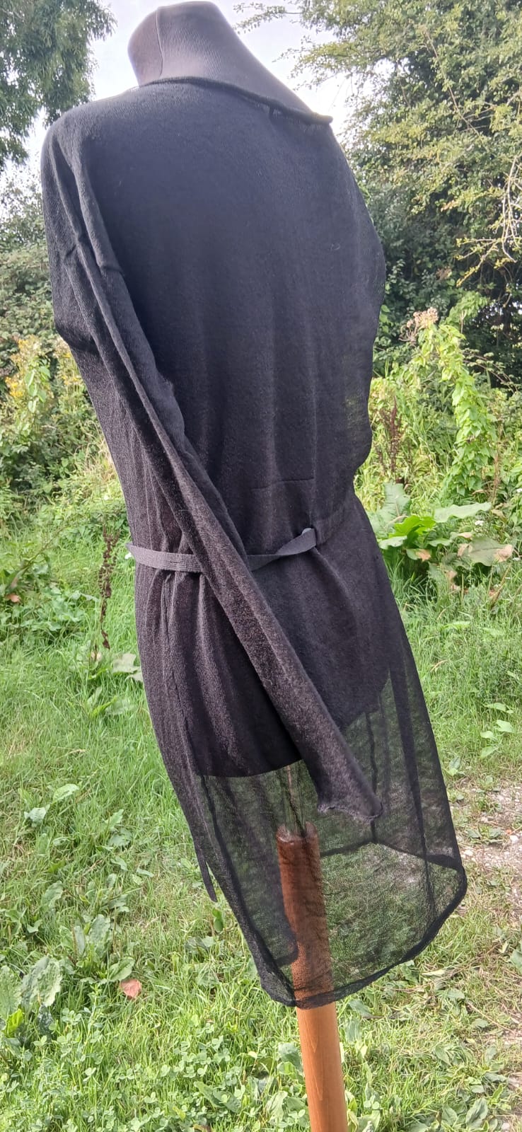A black sheer mesh  dress with a matching black belt tied at the waist. 