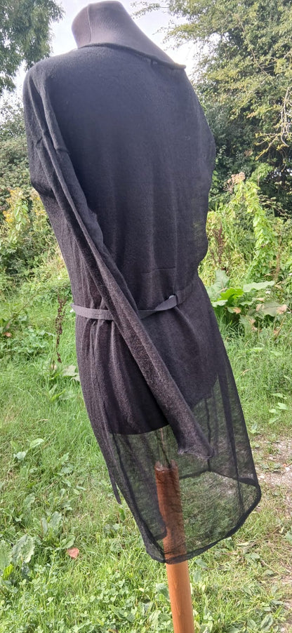 A black sheer mesh  dress with a matching black belt tied at the waist. 