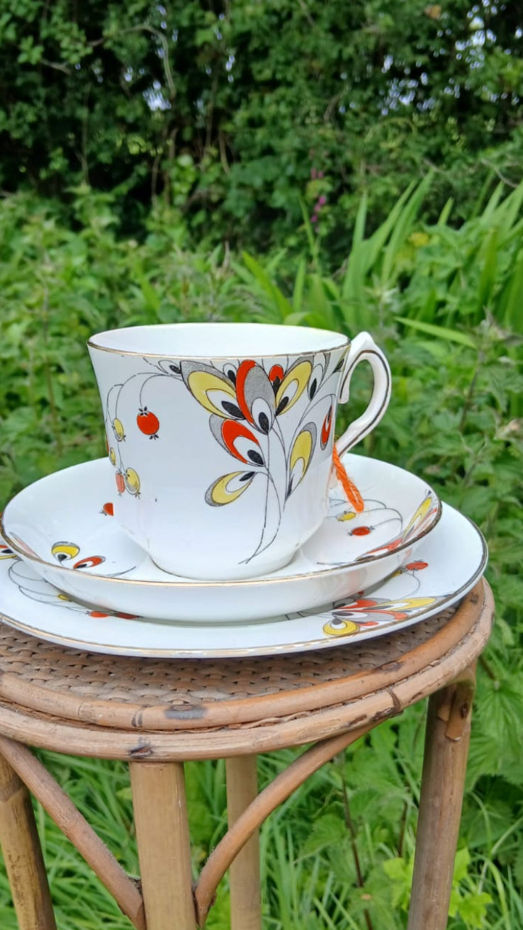 A Wetley China white bone-china porcelain teacup trio with a colorful floral and berries hand painted pattern.