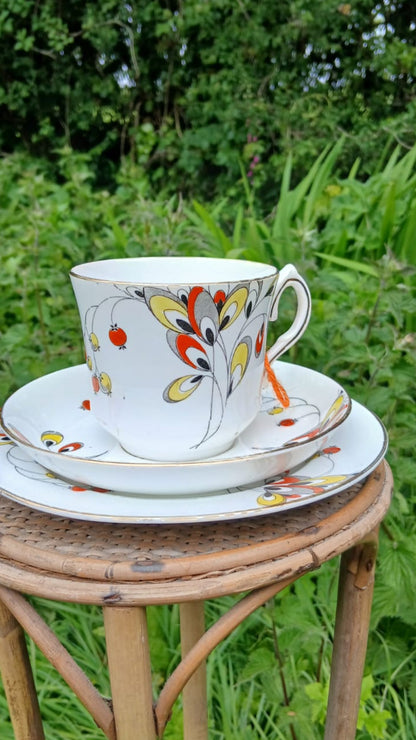 A Wetley China white bone-china porcelain teacup trio with a colorful floral and berries hand painted pattern.