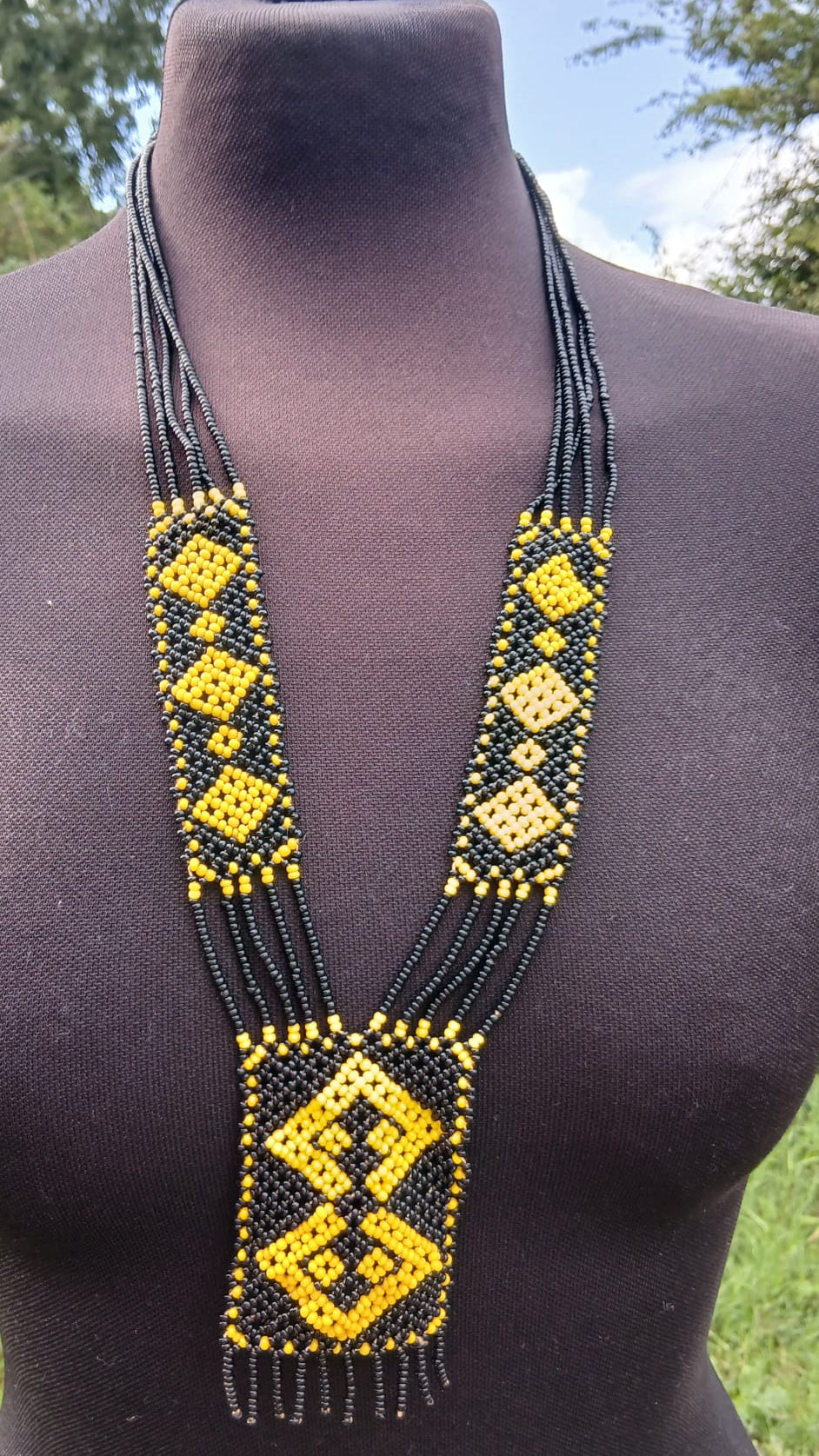 A long beaded necklace with black and yellow geometric patterns.