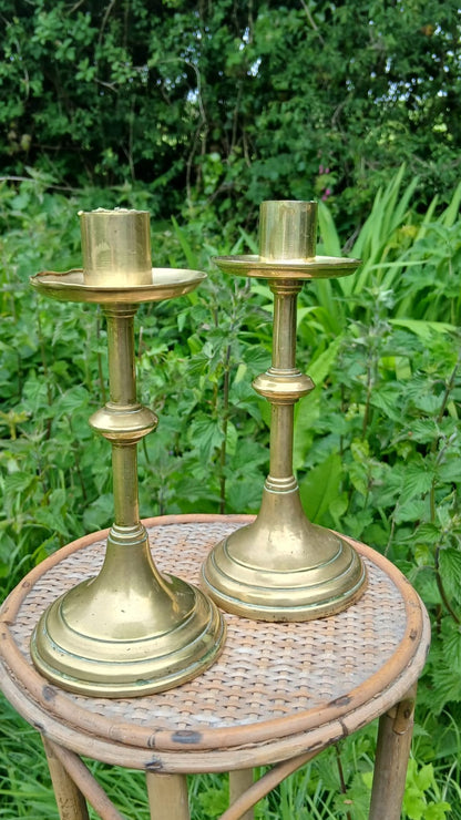 Two vintage brass candlesticks with a polished gold finish featuring baluster stems and round bases.