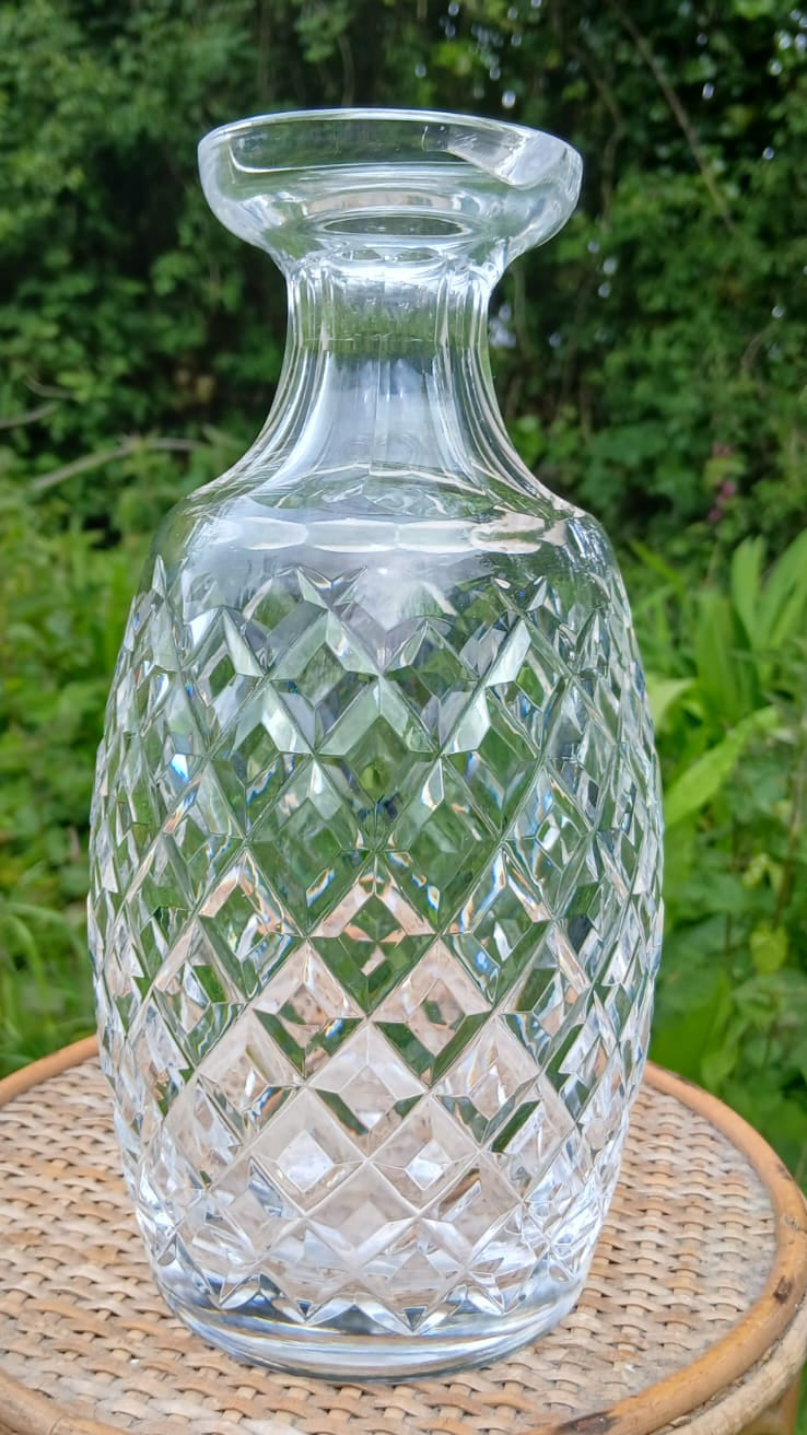 A clear cut-glass decanter with a diamond-patterned body and a short flared neck.