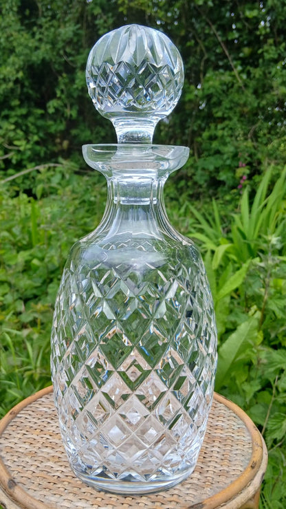 A clear cut-crystal decanter with a matching stopper
