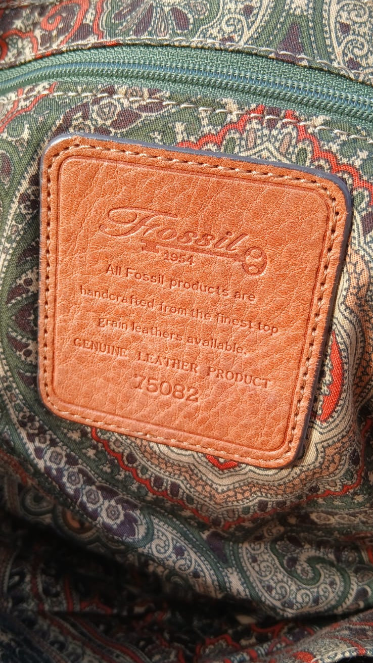 Close-up of a patterned fabric surface with a tan leather patch embossed with the Fossilite brand name.