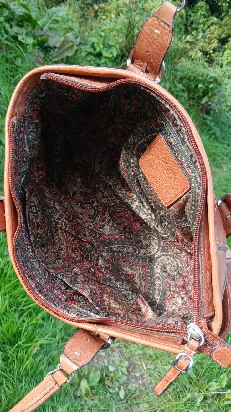 An open brown leather handbag with a paisley-patterned interior lining.