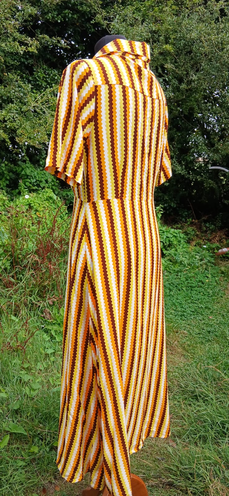 A short-sleeved collared dress with vertical orange, yellow, brown and white wavy stripes by Compañia Fantastica.
