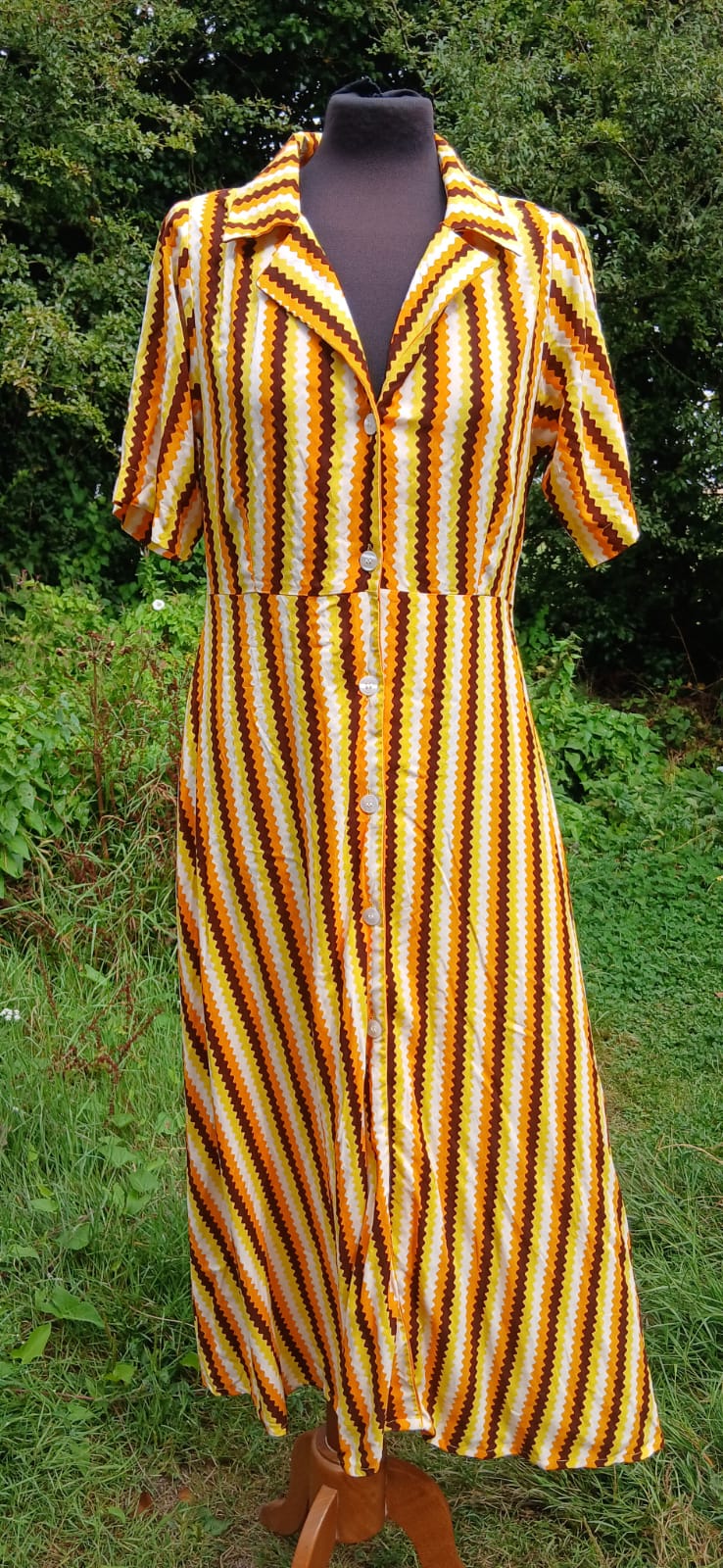 A short-sleeve collared button-front dress with vertical yellow, orange, and brown wavy stripes by  Compañia Fantàstica.
