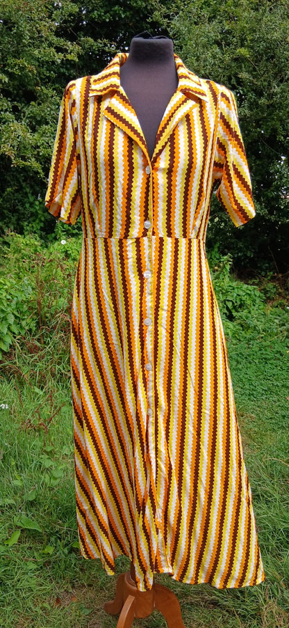 A short-sleeve collared button-front dress with vertical yellow, orange, and brown wavy stripes by  Compañia Fantàstica.