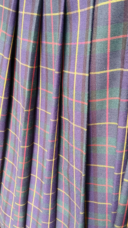 Close-up of a pleated fabric surface with a tartan plaid pattern in blue, green, red and yellow lines.