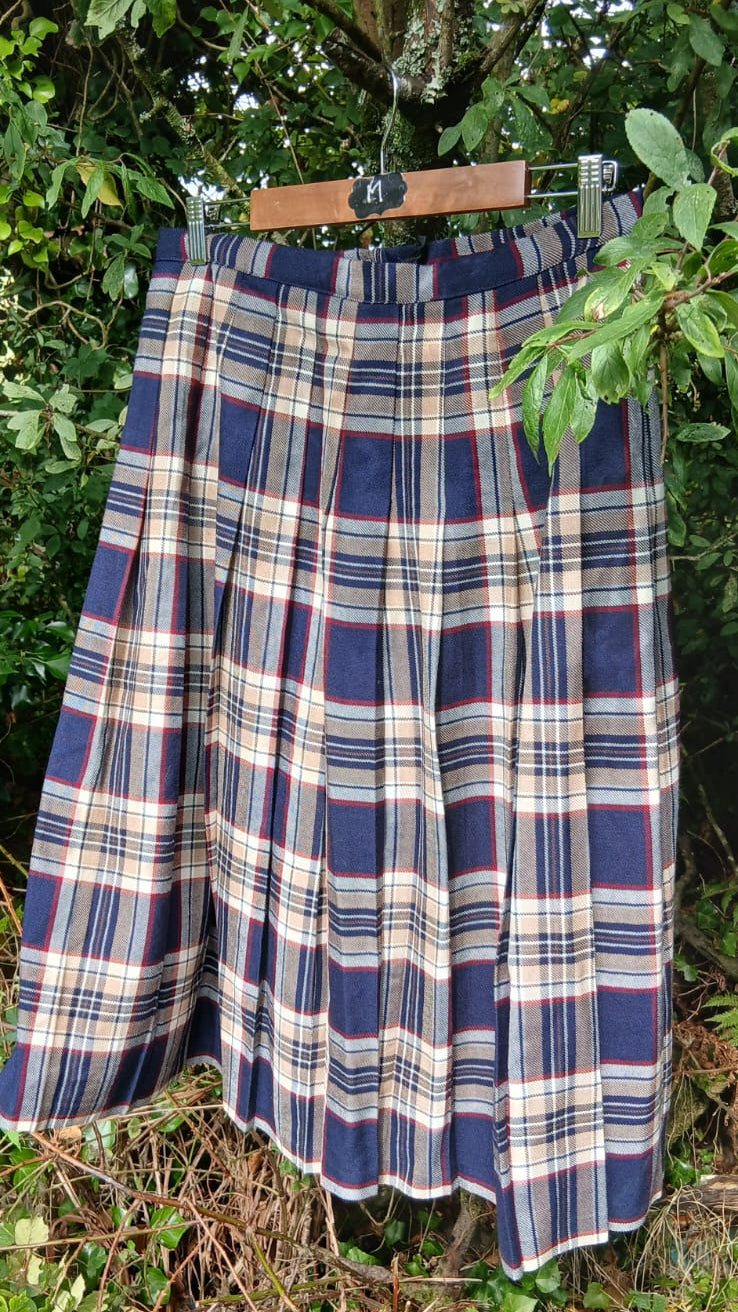 A vintage pleated tartan skirt in navy blue, beige, white and red from the brandb Seven Pride.   