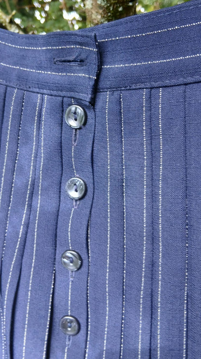 Close-up of a St Micheal navy blue skirt with thin white vertical pinstripes and button-front closure.