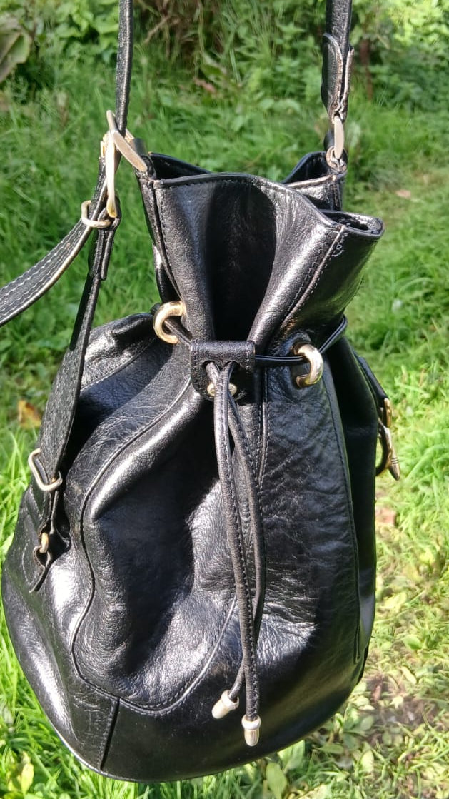A black leather bucket bag with a drawstring closure and gold-tone hardware.