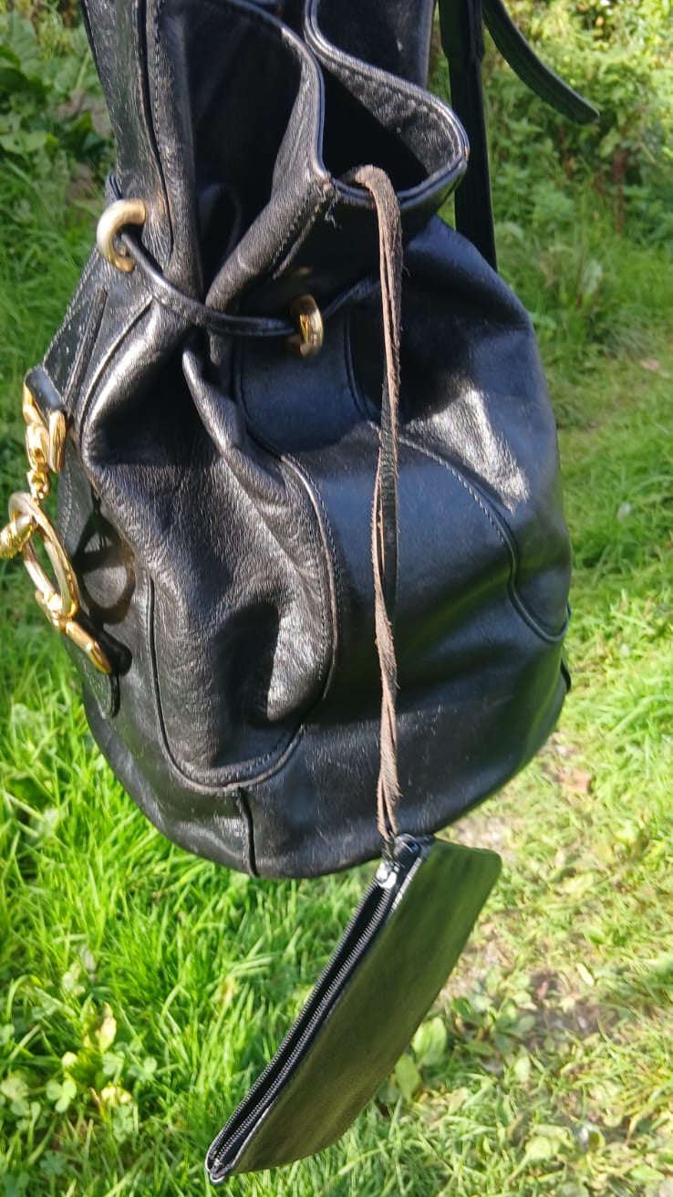 A black leather bucket bag with gold-tone hardware and a drawstring closure.