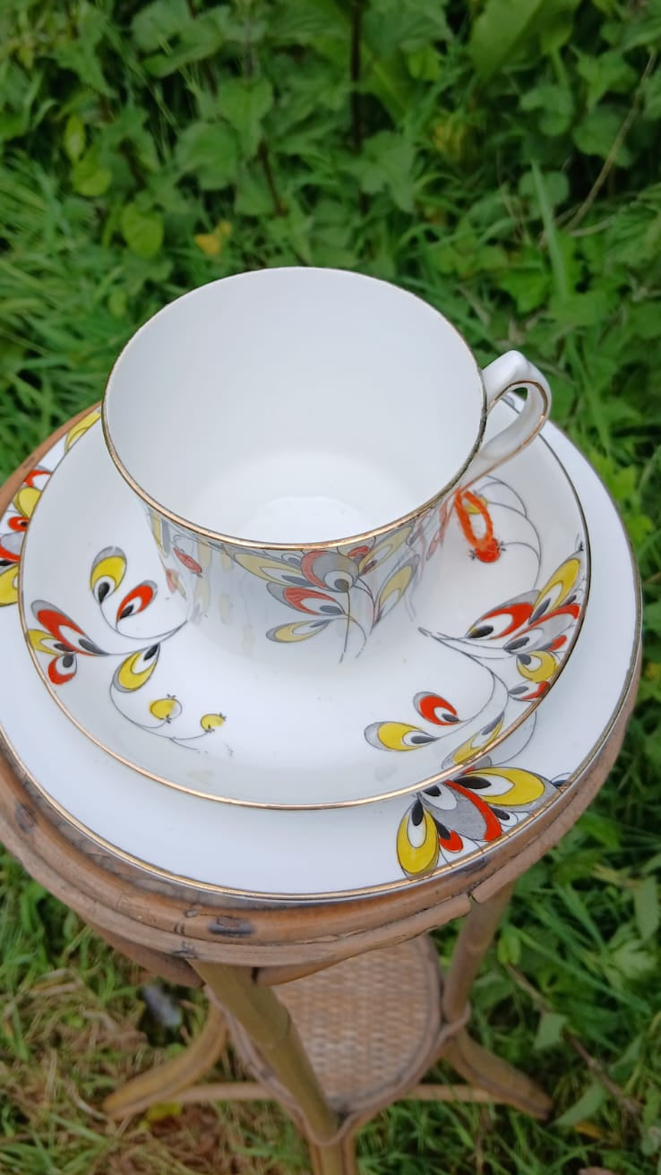 A Wetley China white bone-china porcelain teacup trio with a colorful floral and berries hand painted pattern and gold rim.