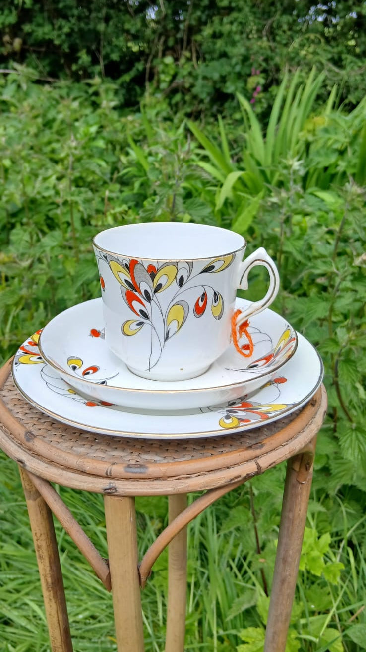 A Wetley China white porcelain teacup trio with a colorful floral pattern.
